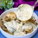 Instant Pot Low-Carb Creamy Garlic Tuscan Chicken Thighs in creamy sauce with parsley in a white bowl