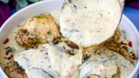 Instant Pot Low-Carb Creamy Garlic Tuscan Chicken Thighs in creamy sauce with parsley in a white bowl
