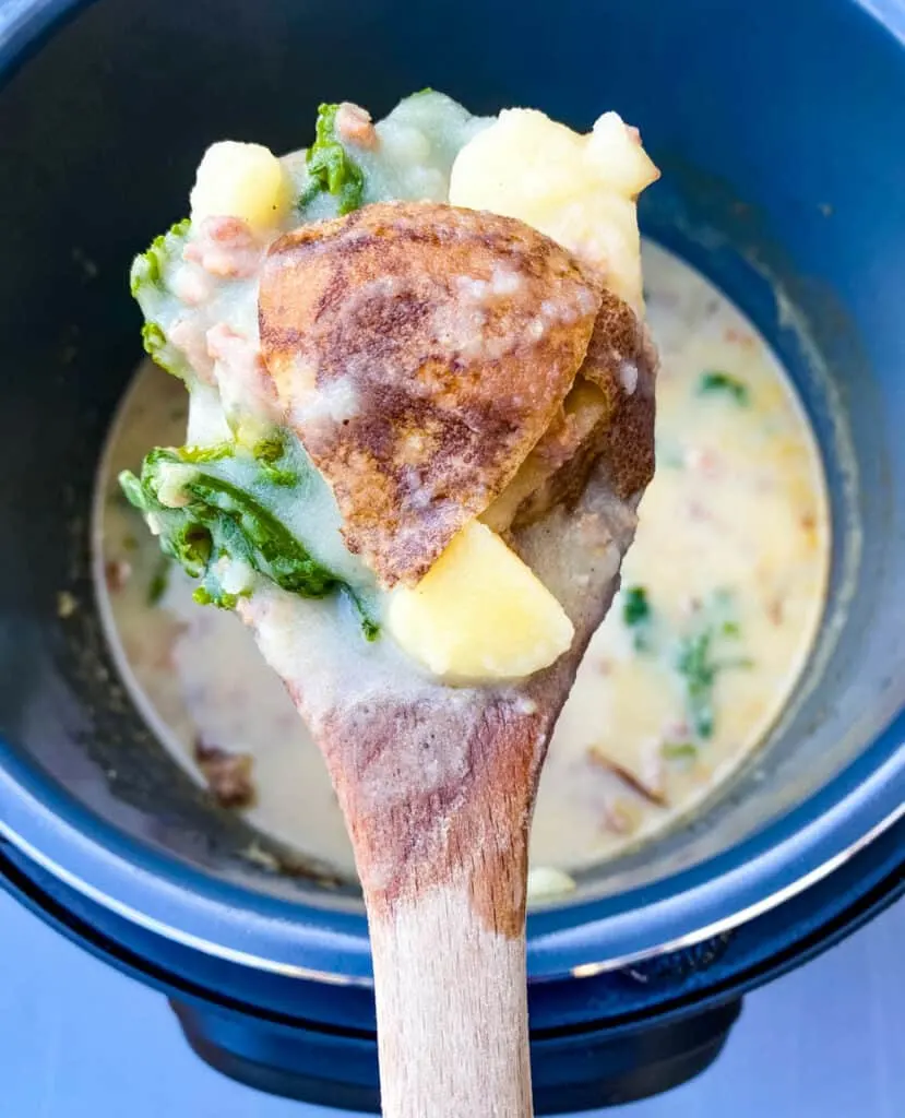 a spoonful of Instant Pot Zuppa Toscana soup with a wooden spoon