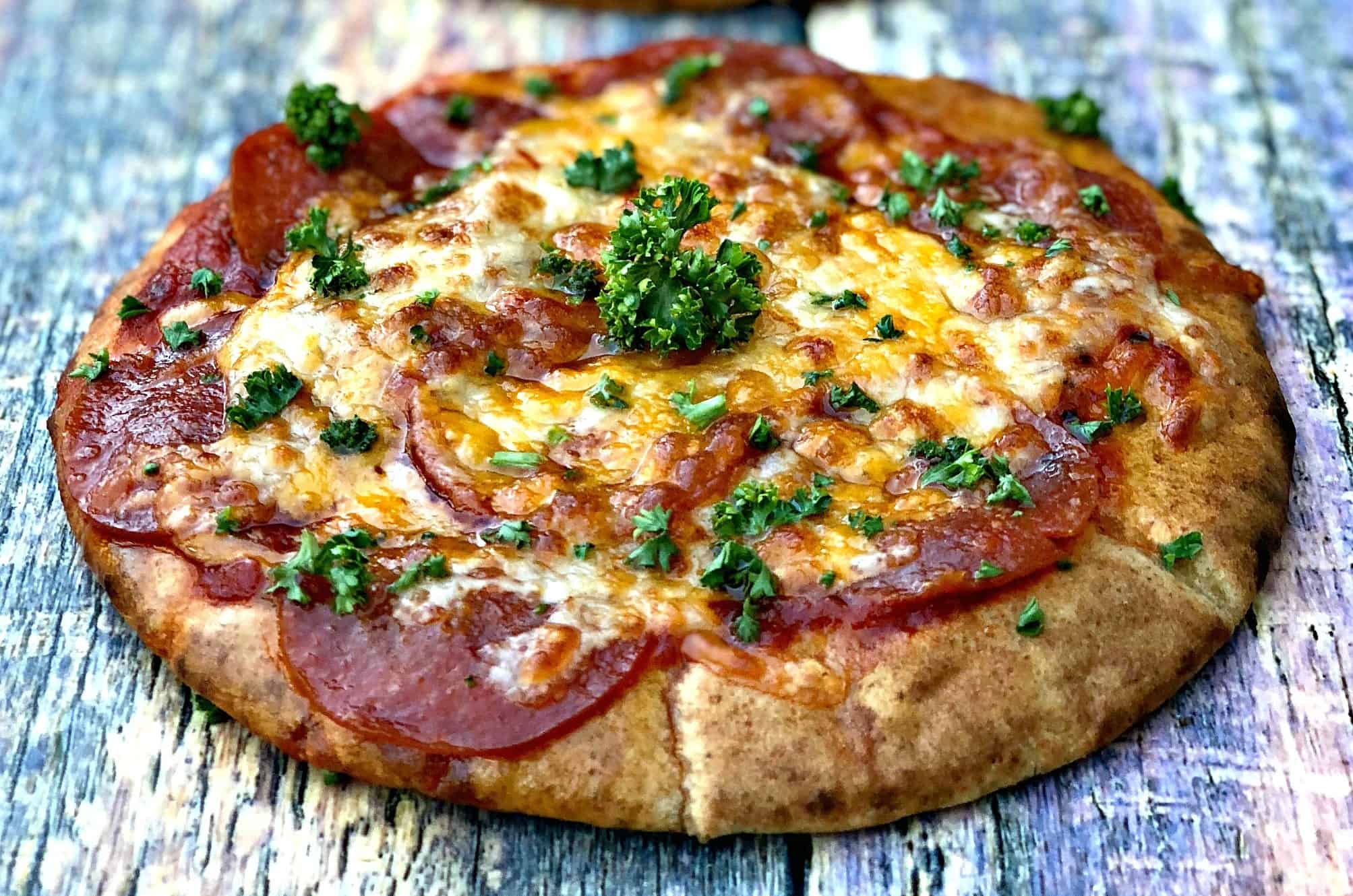 close up of air fryer pepperoni pizza with mozzarella cheese on a multi colored surface