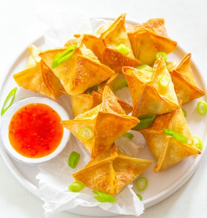 air fryer crab rangoon on a white plate with sauce