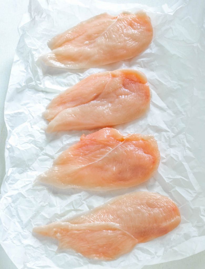 raw chicken cutlets on a flat surface