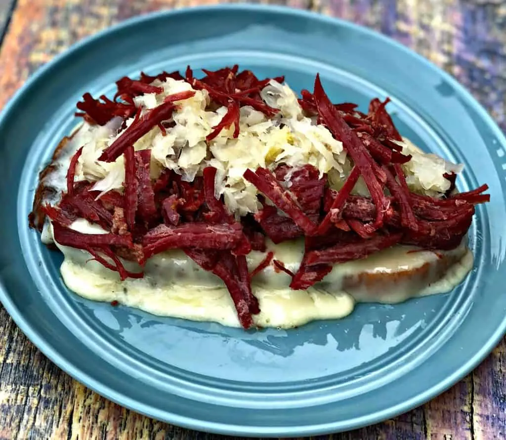 Instant Pot Corned Beef Reuben Sandwich with rye bread, sauerkraut, and thousand island dressing on a blue plate