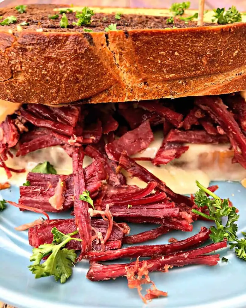 Instant Pot Corned Beef Reuben Sandwich with rye bread, sauerkraut, and thousand island dressing on a blue plate