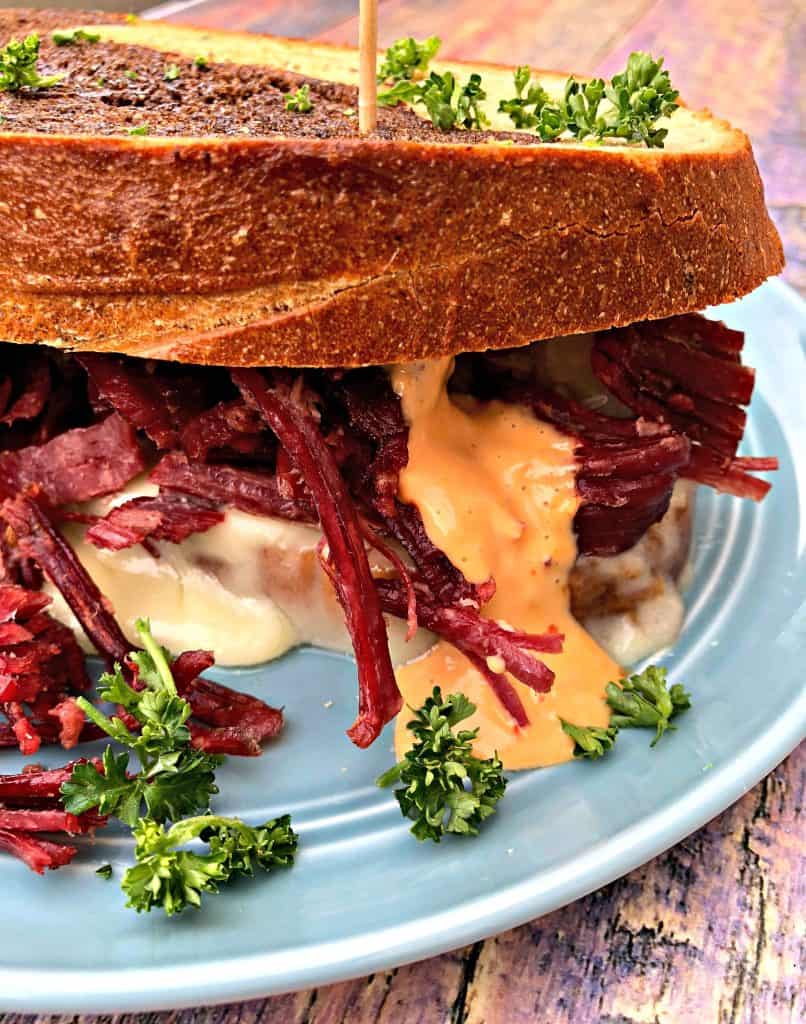Instant Pot Corned Beef Reuben Sandwich with rye bread, sauerkraut, and thousand island dressing on a blue plate
