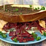 close up of Instant Pot Corned Beef Reuben Sandwich with rye bread, sauerkraut, and thousand island dressing on a blue plate