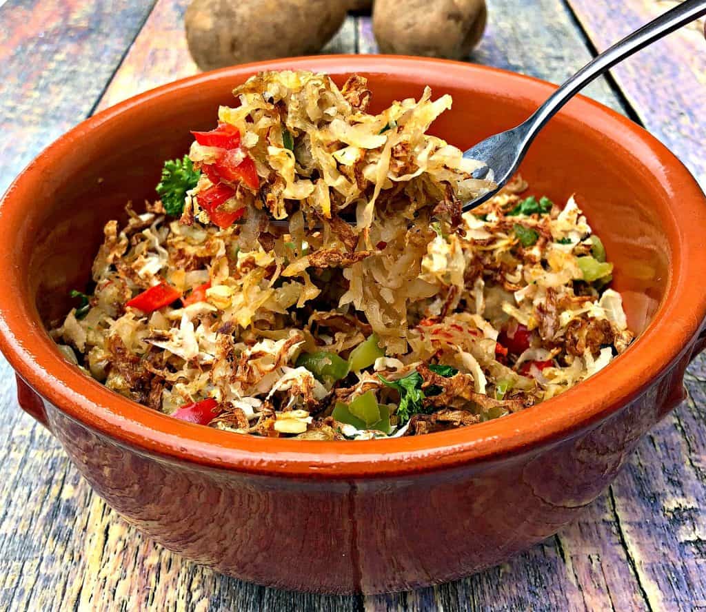 air fryer hash browns in an orange bowl held with a fork