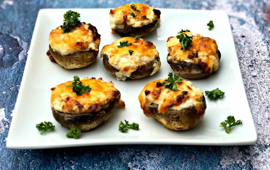 cooked stuffed mushroom with cheese on a white plate