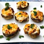 cooked stuffed mushroom with cheese on a white plate