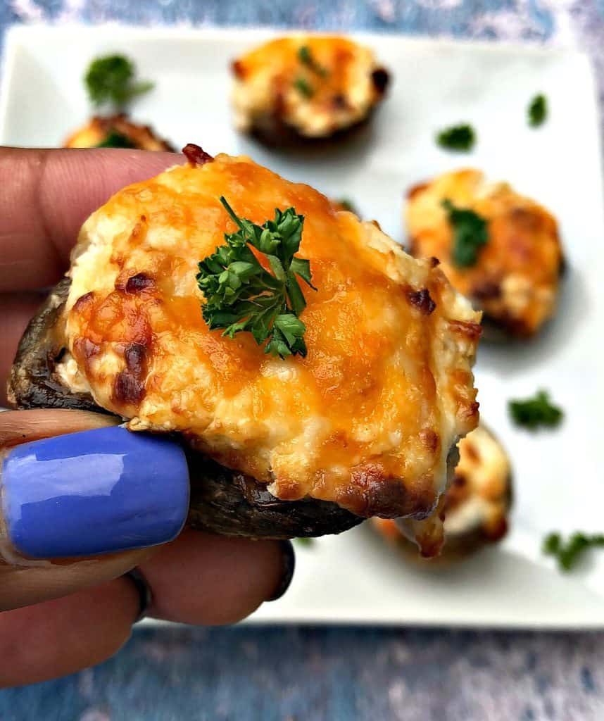 person holding cooked air fryer stuffed mushroom with cheese