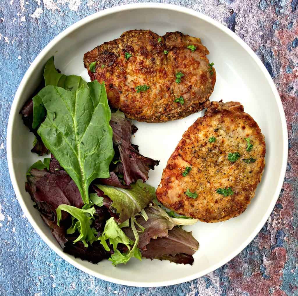 air fryer pork chops in a white bowl with salad