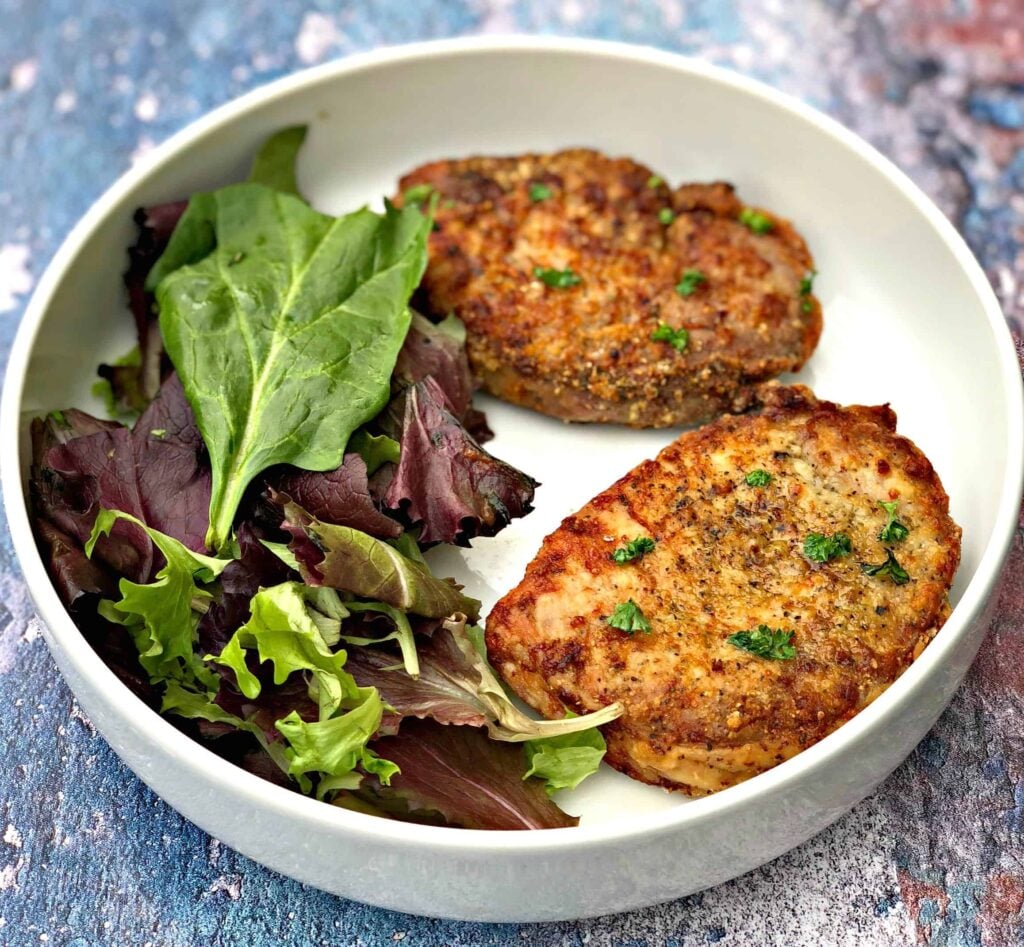 air fryer pork chops in a white bowl with salad