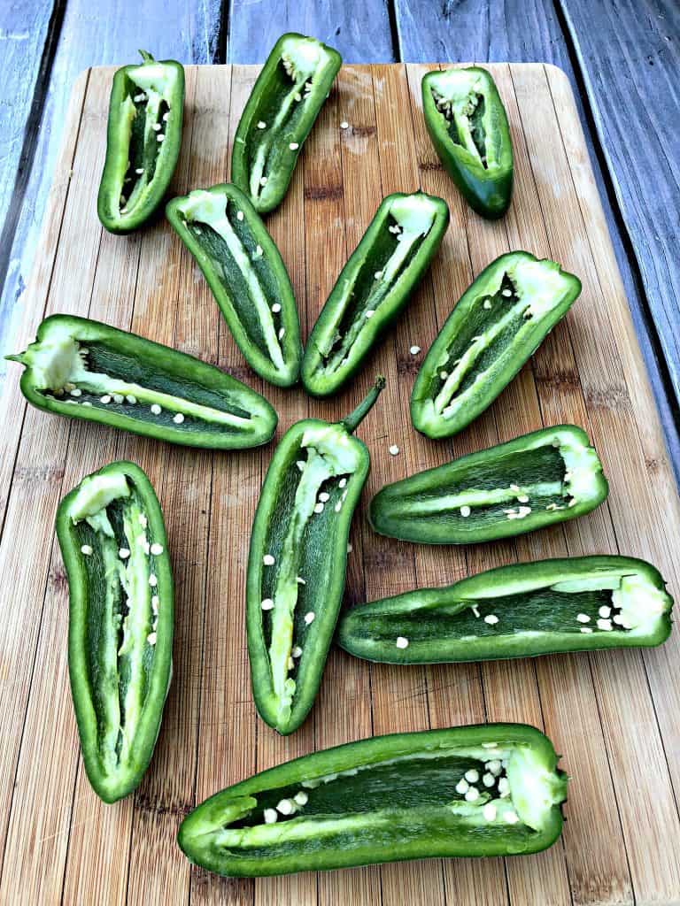 fresh jalapenos sliced in half on a cutting board