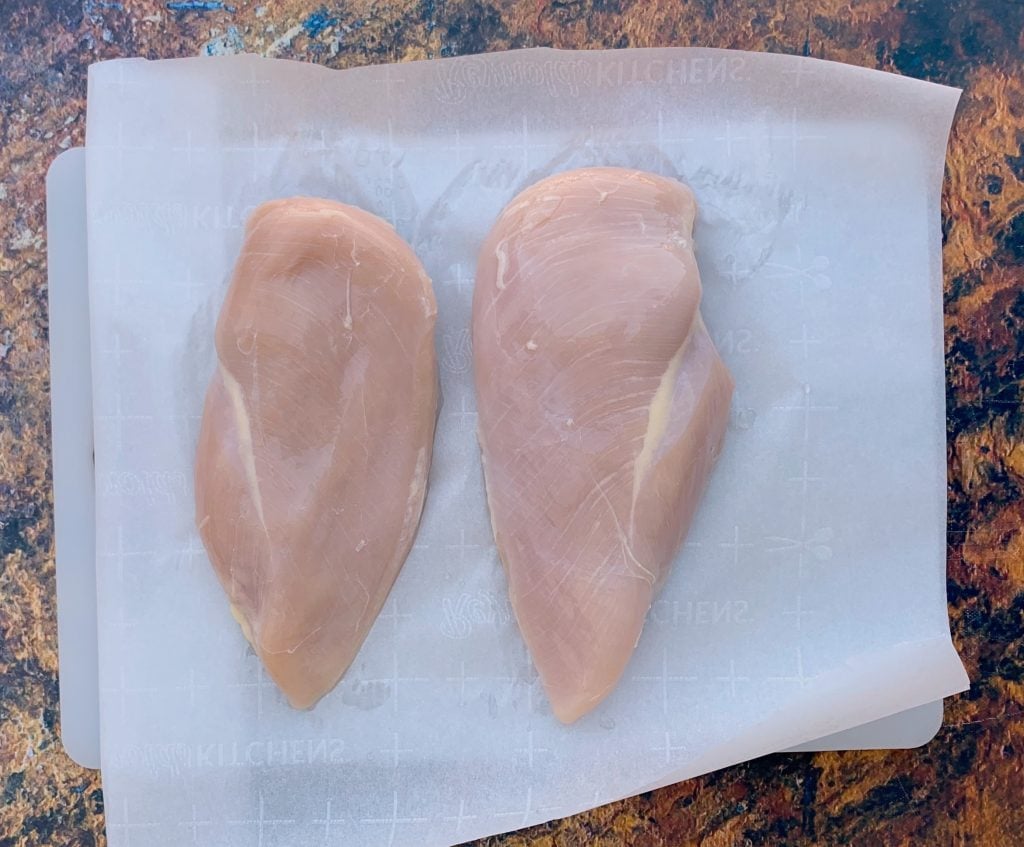 raw chicken breasts on parchment paper
