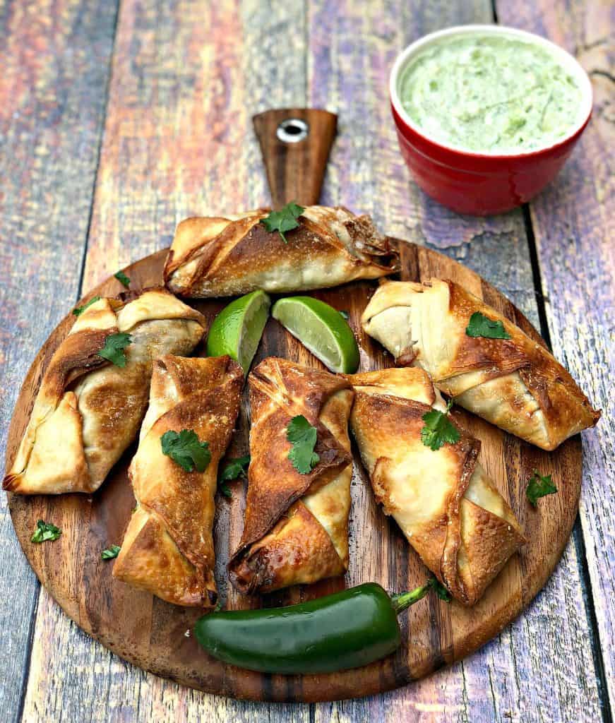 air fryer southwestern egg rolls cut in half with black beans, corn and red peppers spread out on a brown cutting board