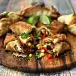 air fryer southwestern egg rolls cut in half with black beans, corn and red peppers spread out on a brown cutting board