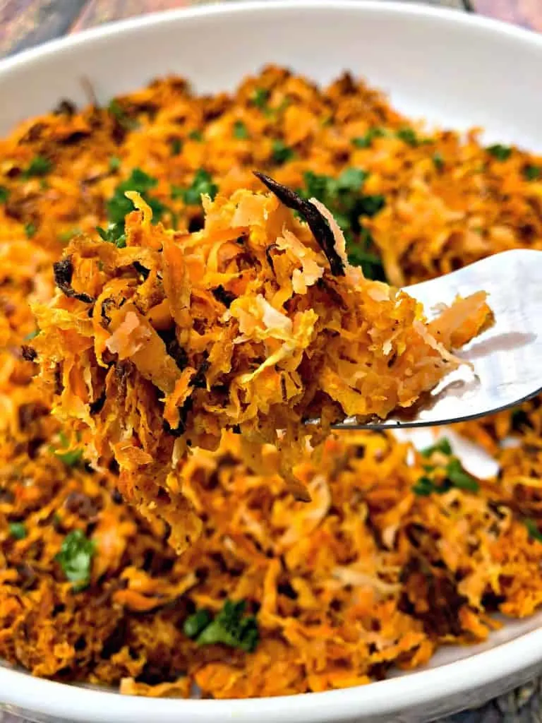sweet potato hash browns scooped with a fork in a white bowl