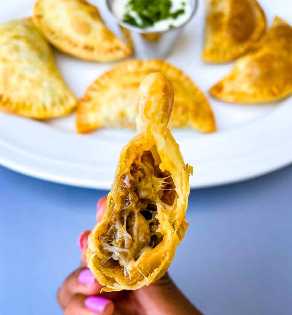 person holding beef and cheese empanada