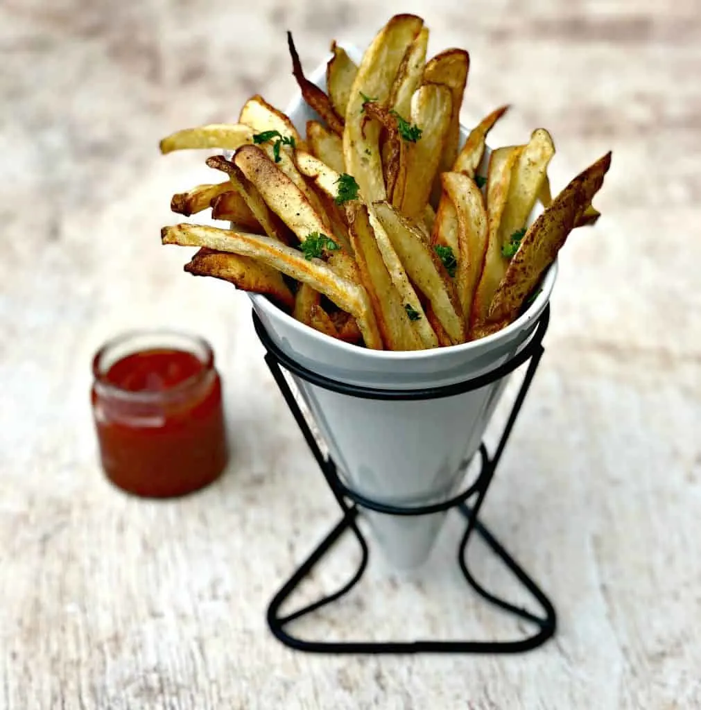 air fryer fries spread out on a brown surface with ketchup