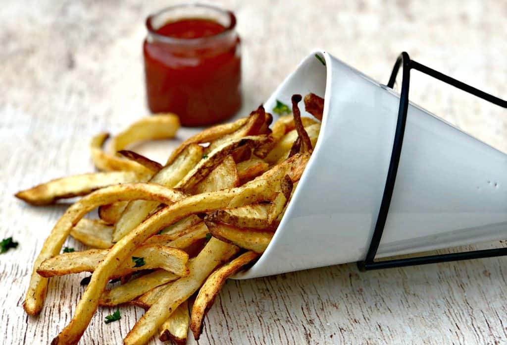 air fryer fries spread out on a brown surface with ketchup
