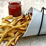 air fryer fries spread out on a brown surface with ketchup