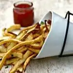 air fryer fries spread out on a brown surface with ketchup