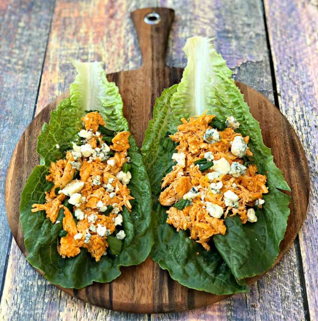 buffalo chicken wraps on romaine lettuce on a cutting board with blue cheese