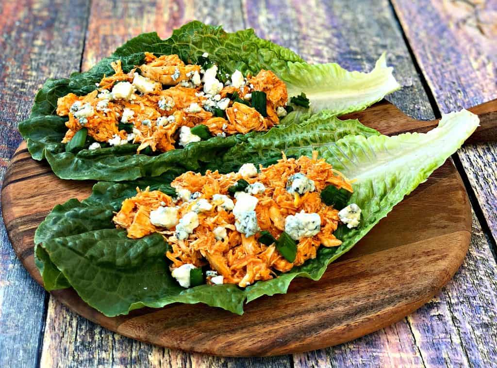 buffalo chicken wraps on romaine lettuce on a cutting board with blue cheese