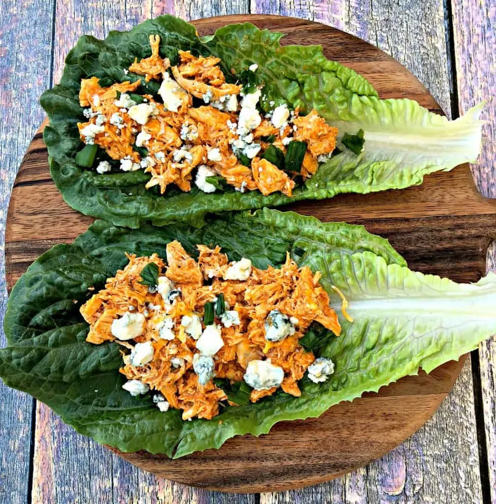 buffalo chicken wraps on romaine lettuce on a cutting board with blue cheese
