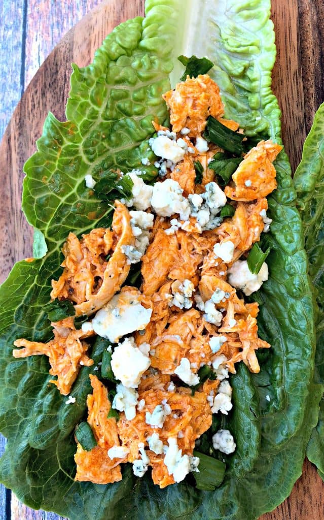 buffalo chicken wraps on romaine lettuce on a cutting board with blue cheese