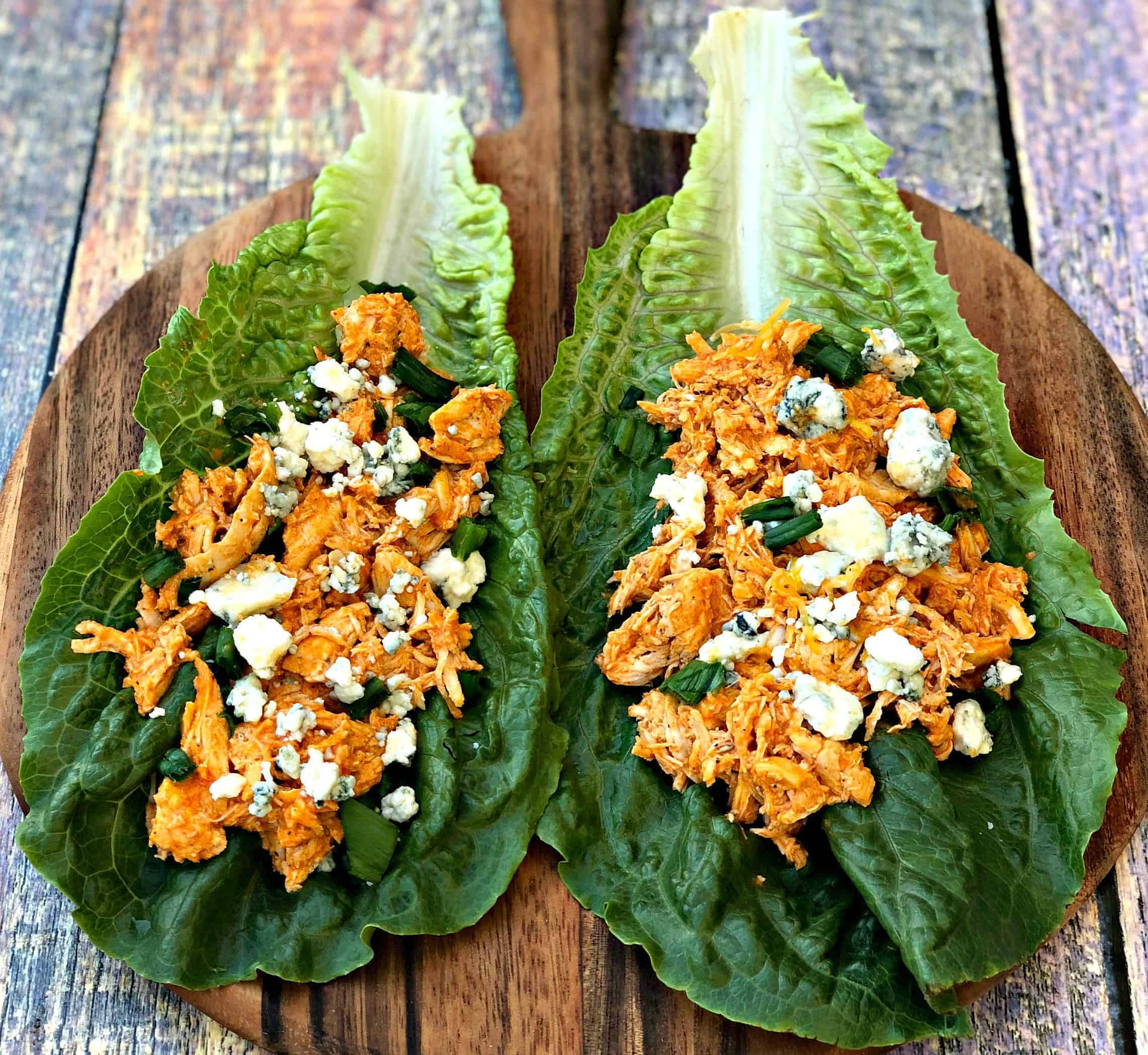 buffalo chicken wraps on romaine lettuce on a cutting board with blue cheese