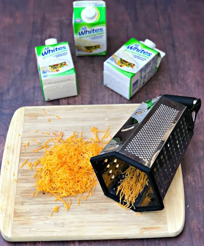 shredded cheese on a cutting board with a cheese grater