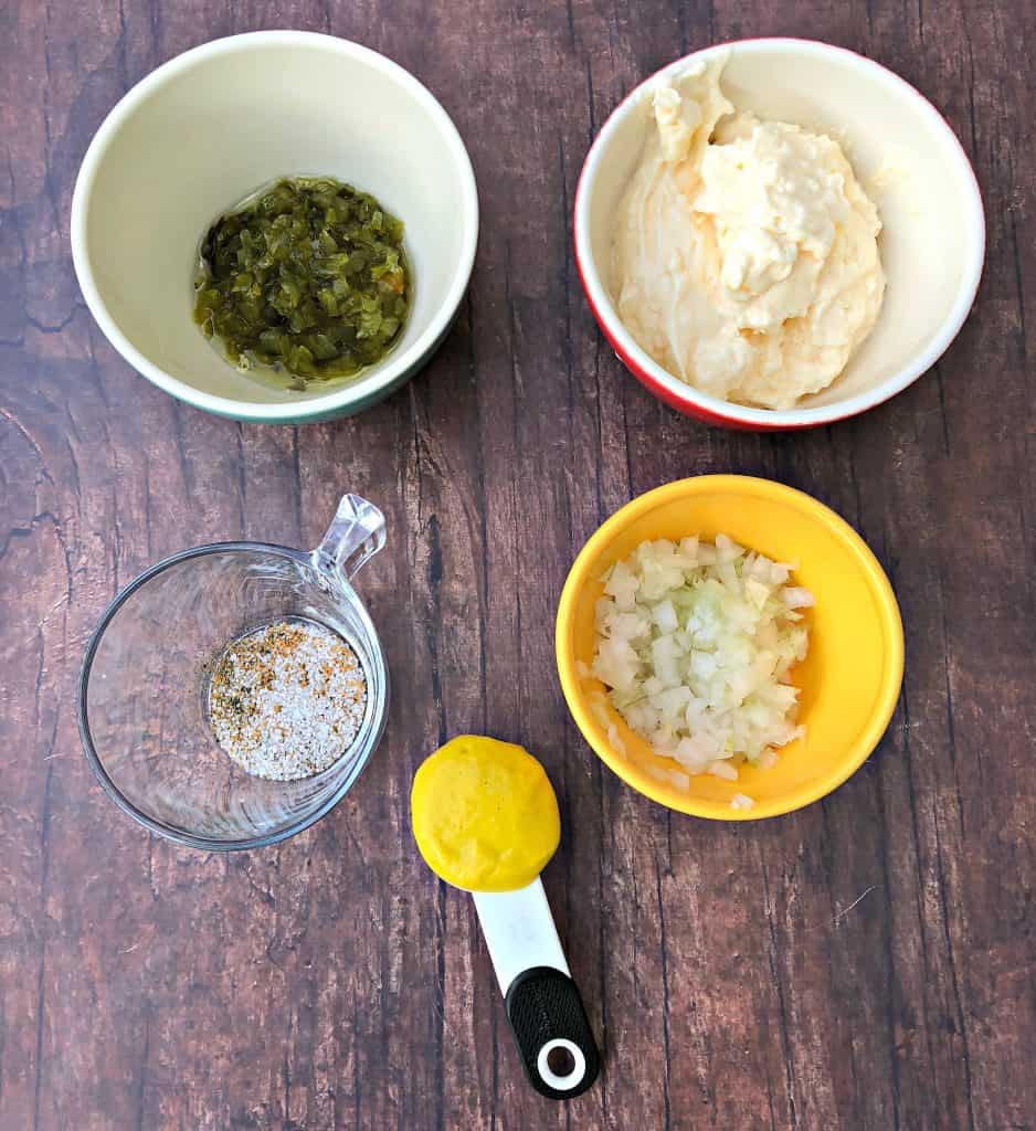 mayo, mustard, and relish in bowls on a brown surface