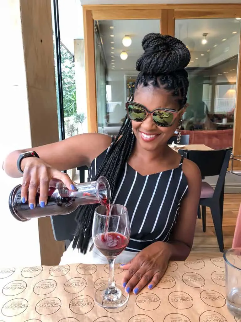 person pouring red wine in greece