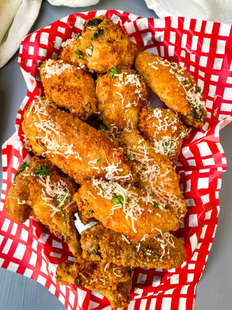 garlic parmesan wings in a bowl wrapped in a red and white napkin