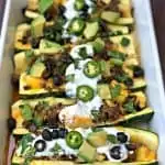 zucchini nachos with olives and sour cream in a baking dish