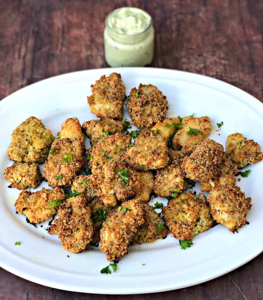 2 keto bacon chicken nuggets on a white plate with avocado ranch