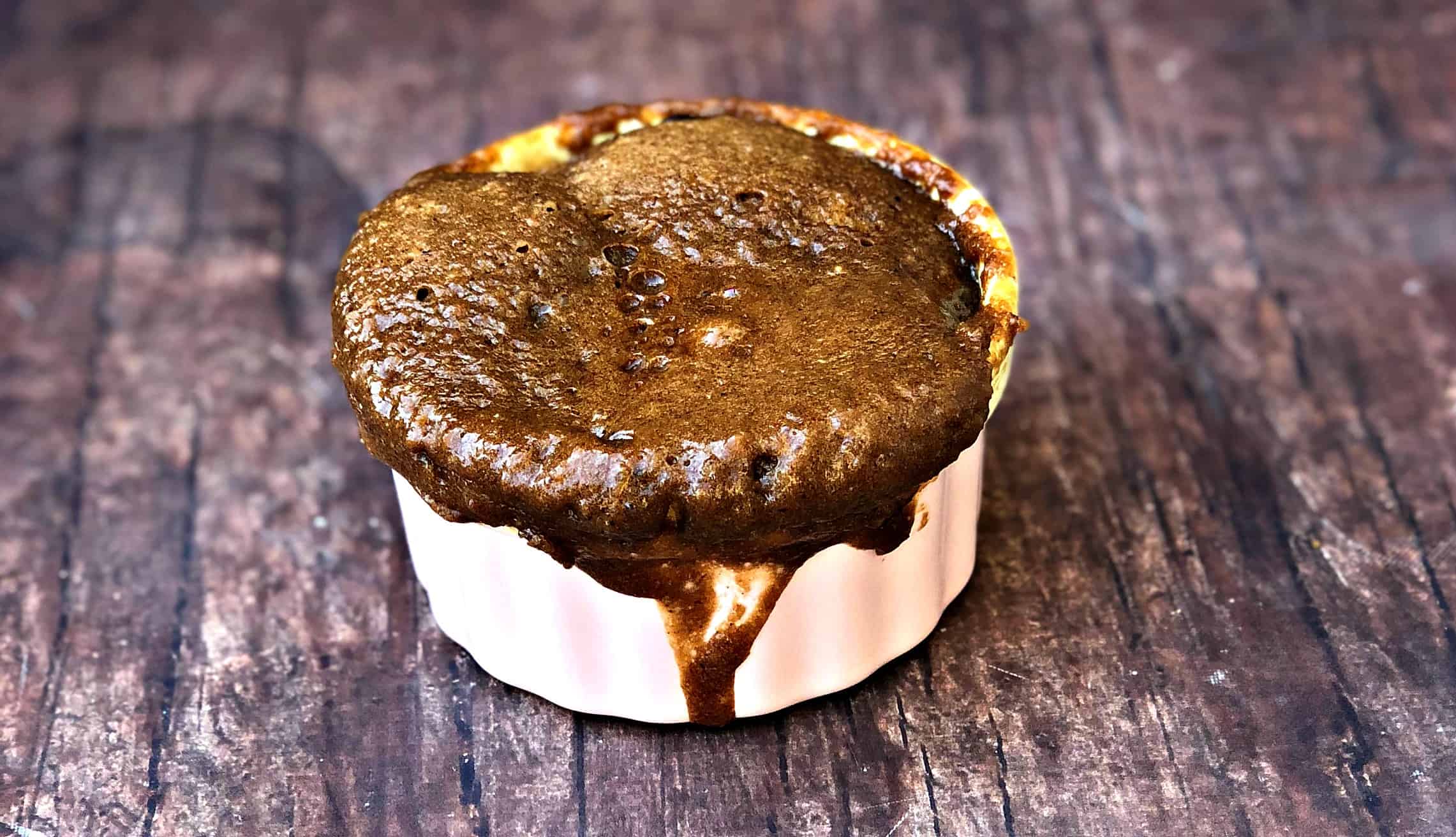 close up of keto peanut butter chocolate chip mug cake in a pink ramekin