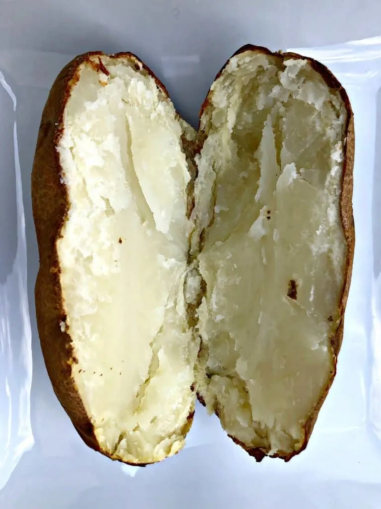 baked potato sliced in half on a white plate