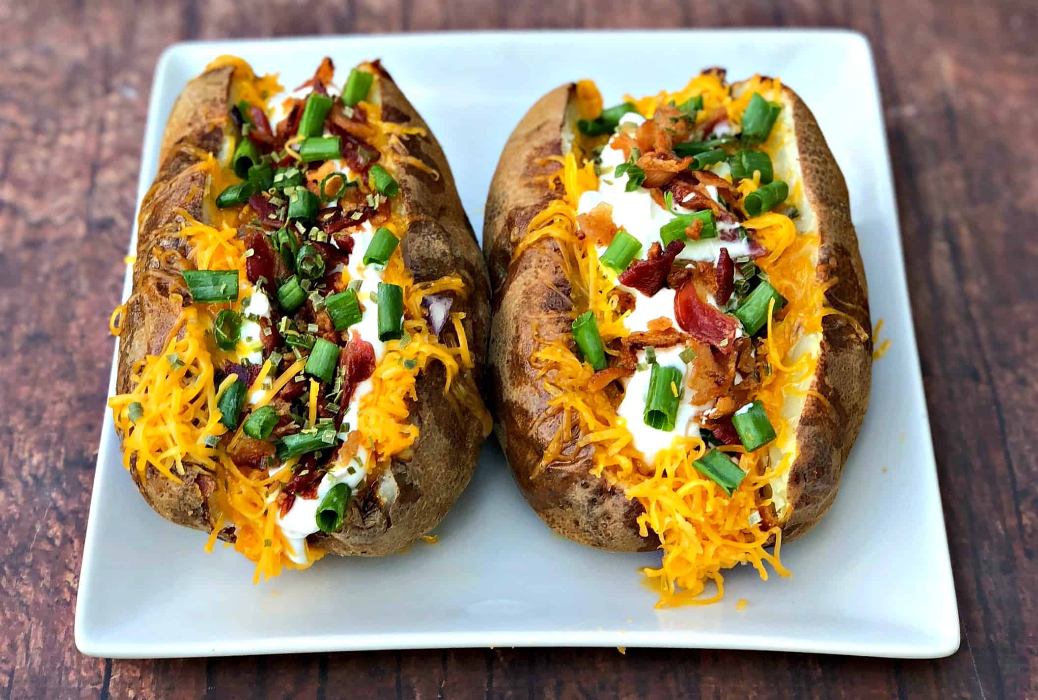 air fryer loaded baked potato on a white plate