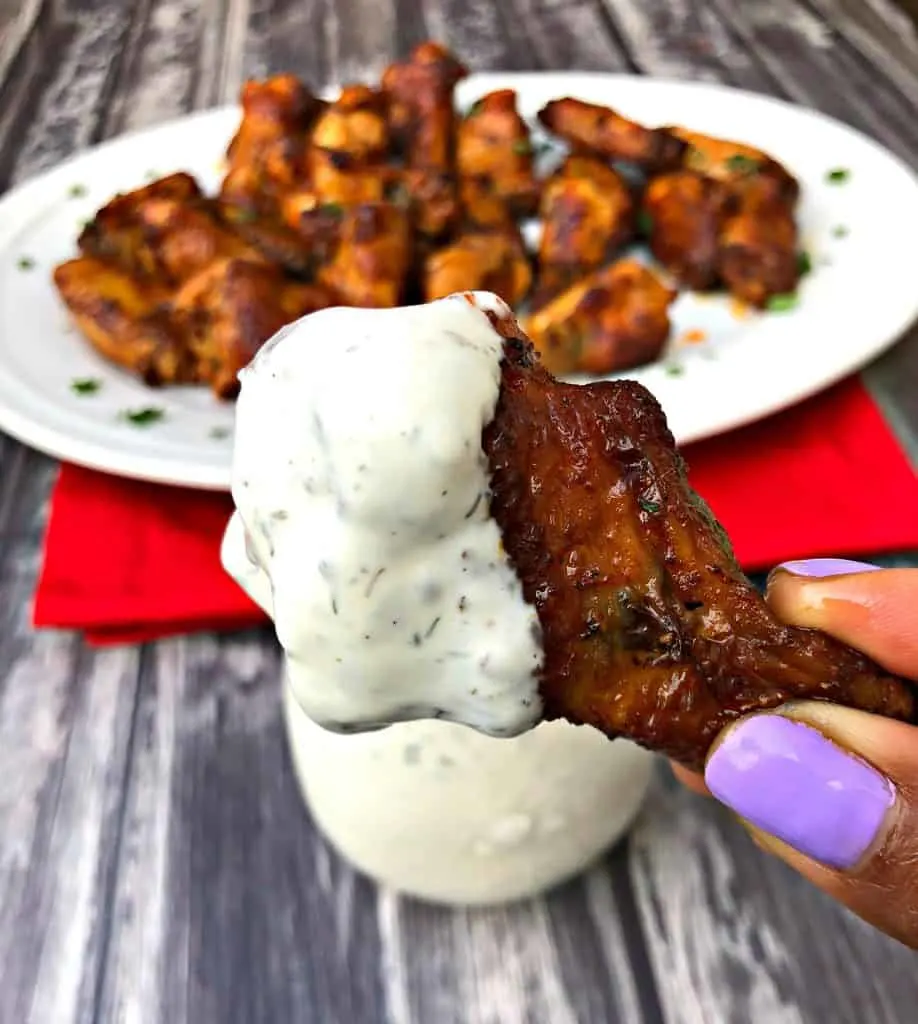person holding air fryer buffalo chicken wing with ranch