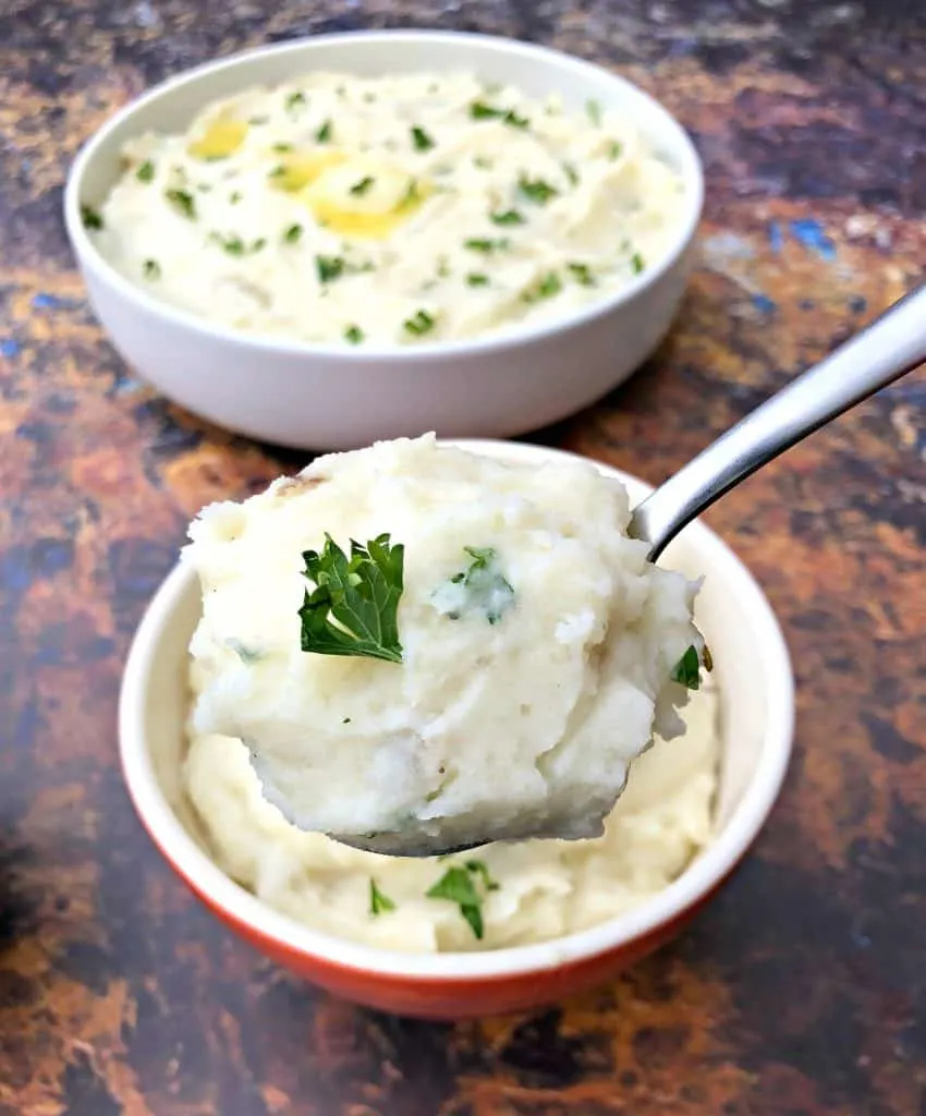 a spoonful of instant pot mashed potatoes with bowls