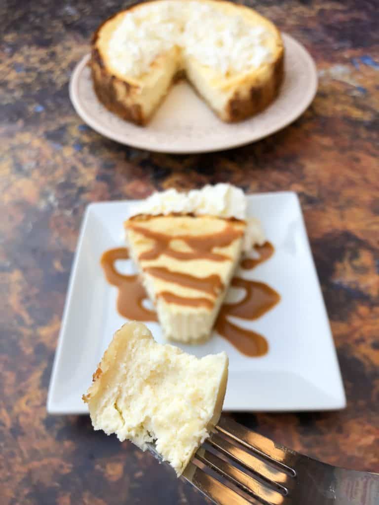 Low-Carb Sugar-Free Keto Cheesecake is a quick and easy ketogenic dessert recipe that is practically carb free and perfect for keto diets and a ketosis lifestyle. This is the best cheesecake recipe and has a delicious gluten-free almond flour crust. You can also prepare the recipe crustless with no crust. keto cheesecake low carb on a white plate with caramel and whipped cream