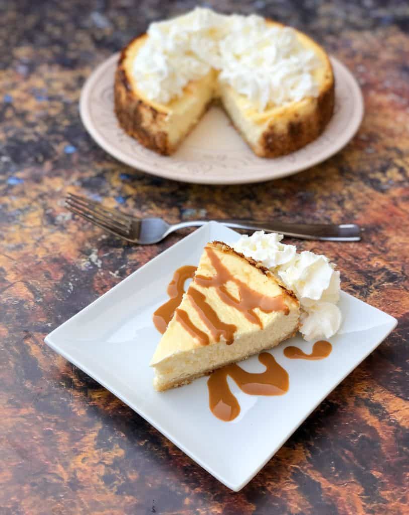 Low-Carb Sugar-Free Keto Cheesecake is a quick and easy ketogenic dessert recipe that is practically carb free and perfect for keto diets and a ketosis lifestyle. This is the best cheesecake recipe and has a delicious gluten-free almond flour crust. You can also prepare the recipe crustless with no crust. keto cheesecake low carb on a white plate with caramel and whipped cream