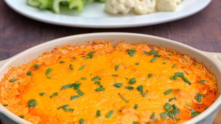 keto low carb buffalo chicken dip in a bowl, plate of celery and cauliflower
