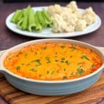 keto low carb buffalo chicken dip in a bowl, plate of celery and cauliflower