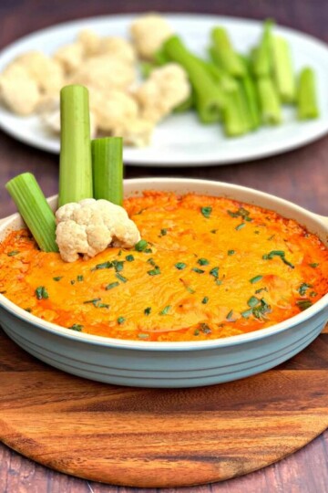 keto low carb buffalo chicken dip in a bowl, plate of celery and cauliflower