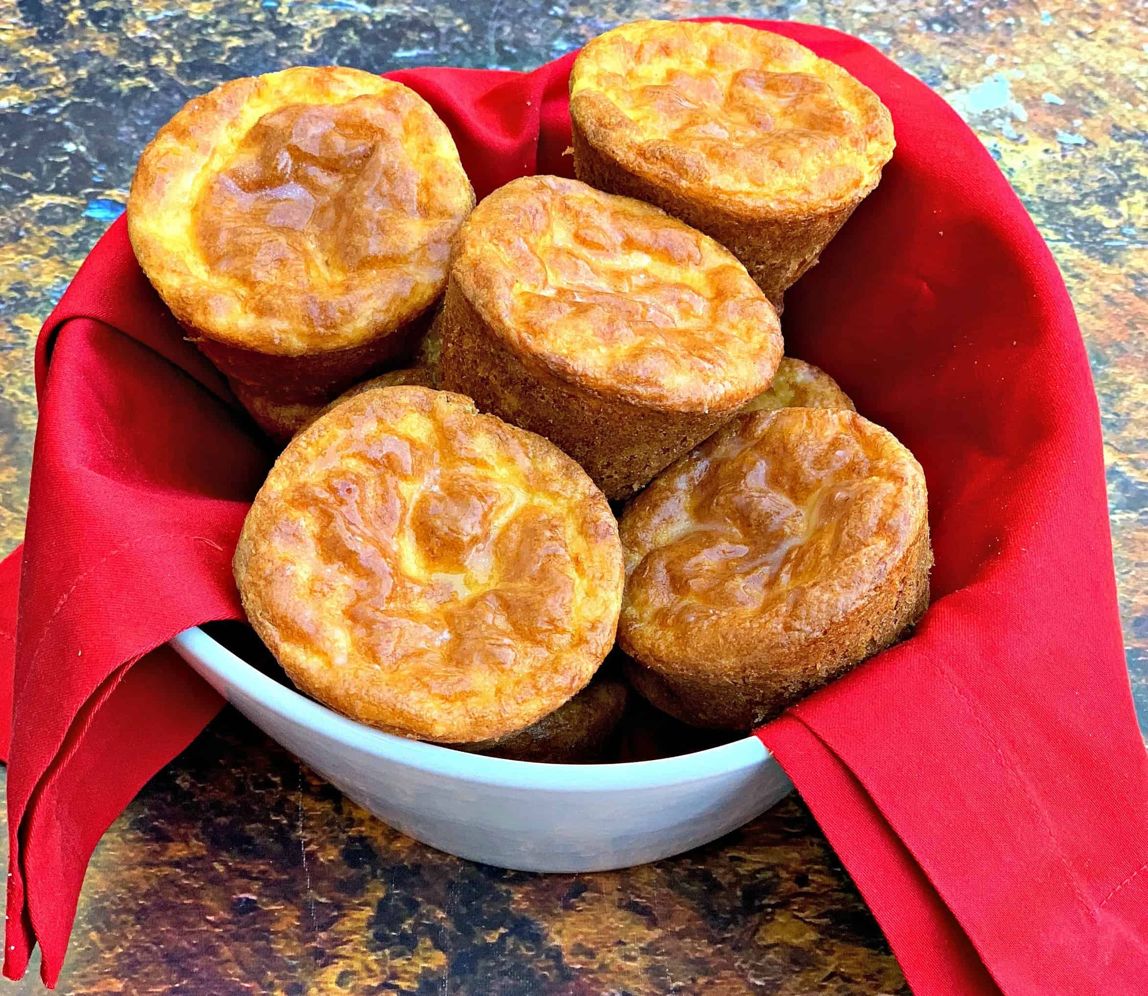 keto low carb cheesy biscuits in a white bowl lined with a red cloth napkin