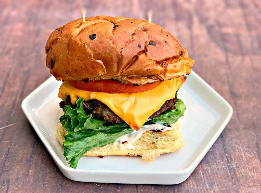 jugosas hamburguesas con queso airfryer en un bollo y plato blanco