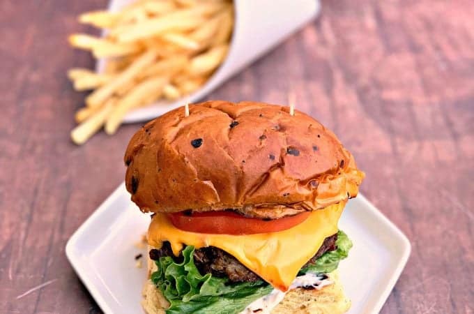 juicy air fryer cheeseburgers on a bun and white plate with fries